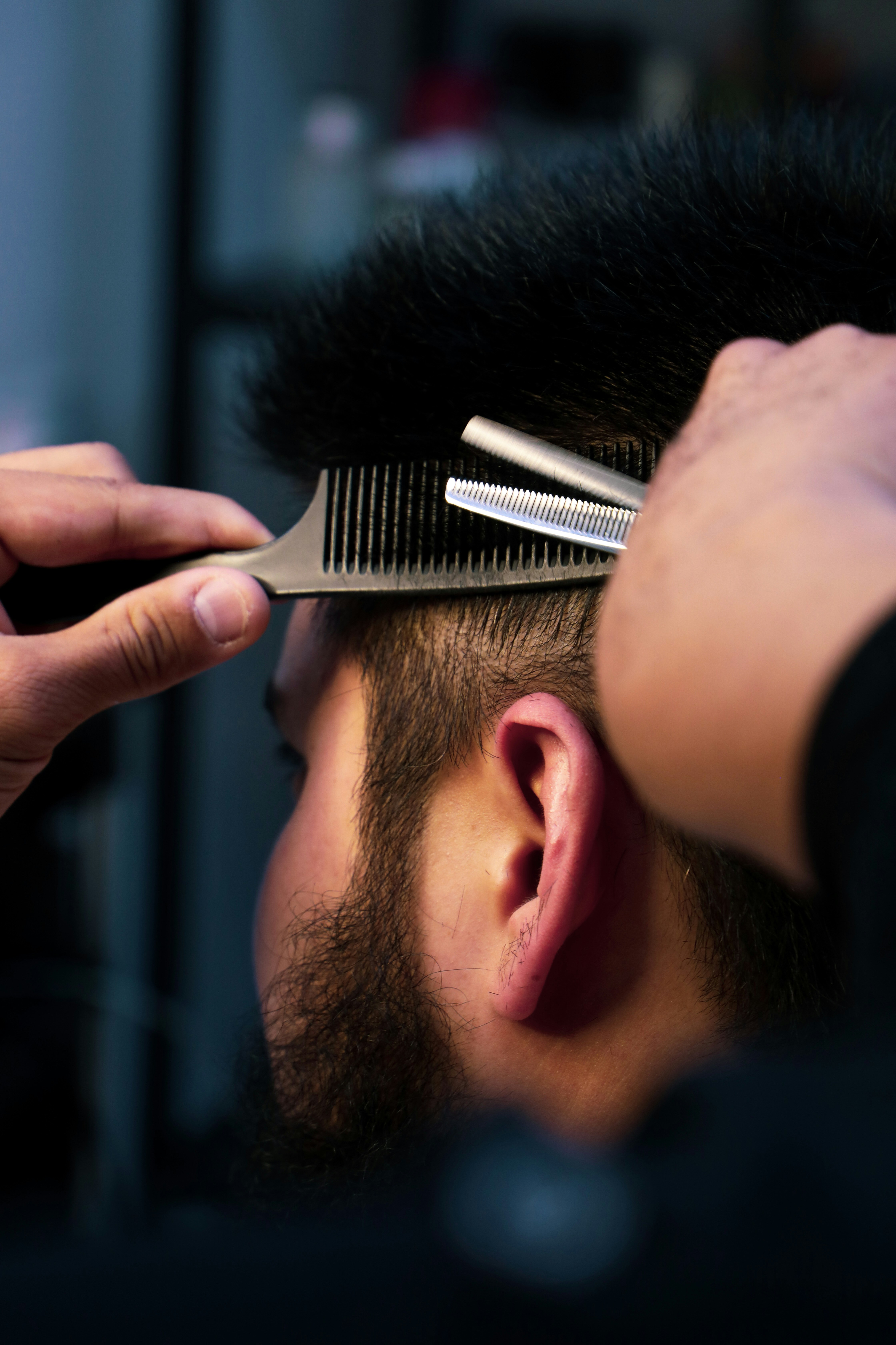 Barber trimming a customer's hair with a comb and scissors